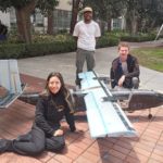 Three Viterbi students pose in front of their 8-foot plane